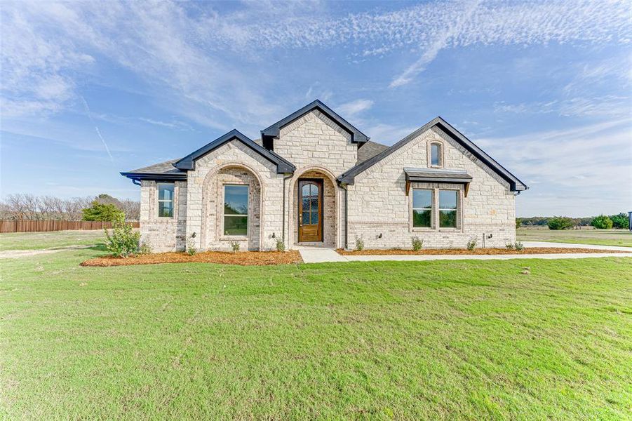 French country inspired facade with a front yard