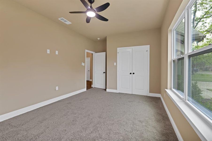 Unfurnished bedroom featuring carpet floors, multiple windows, and visible vents Unfurnished bedroom featuring carpet floors, multiple windows, and visible vents