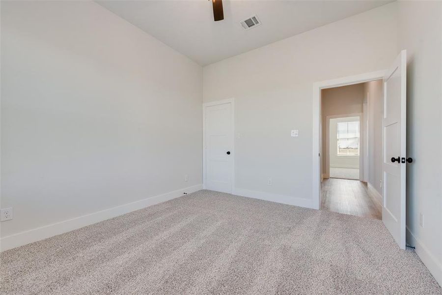 Carpeted room featuring a vaulted ceiling with a ceiling fan, white trim, and a white interior door with a black doorknob
