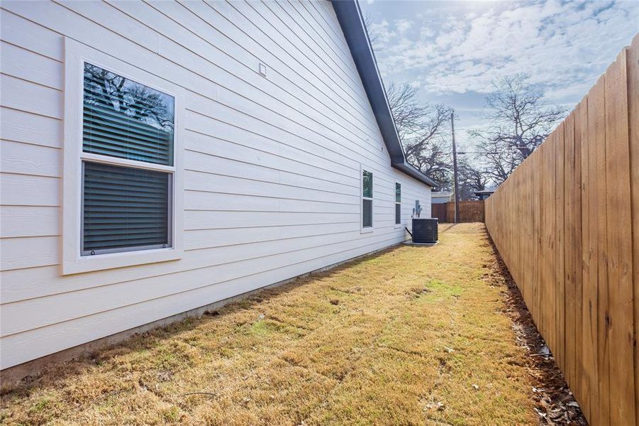 View of side of home featuring a fenced backyard and a cooling unit