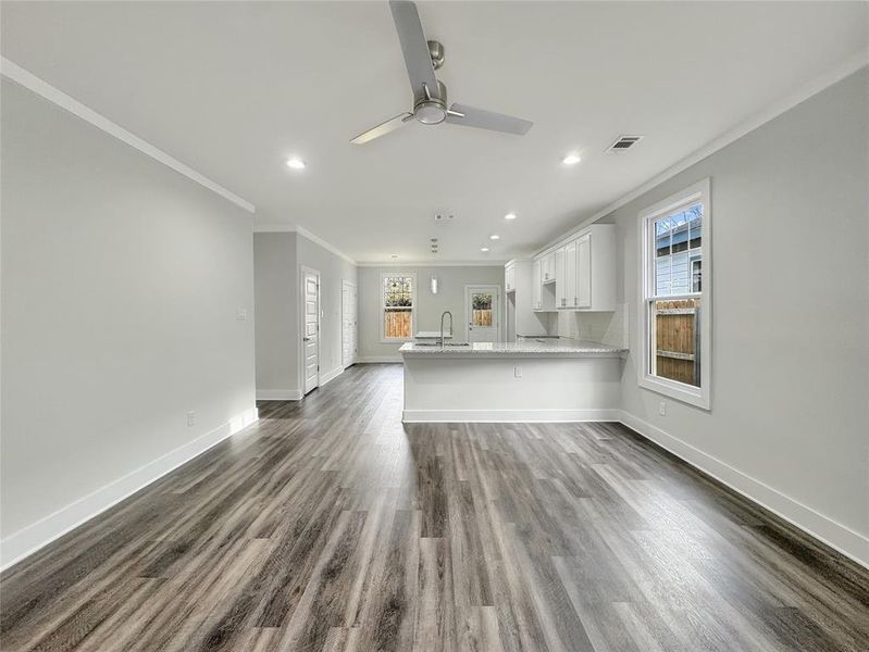 Unfurnished living room with recessed lighting, dark wood-style floors, crown molding, and a ceiling fan Unfurnished living room with recessed lighting, dark wood-style floors, crown molding, and a ceiling fan