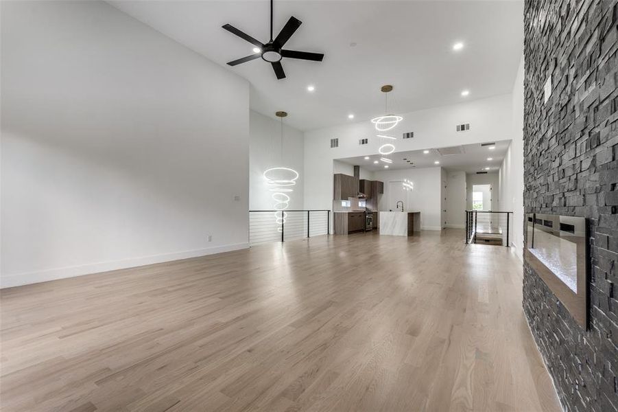 Unfurnished living room featuring high vaulted ceiling, a ceiling fan, a fireplace, recessed lighting, and light wood-style floors