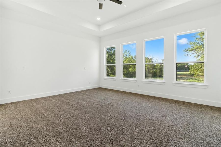 Unfurnished room with dark carpet, a tray ceiling, recessed lighting, and a ceiling fan