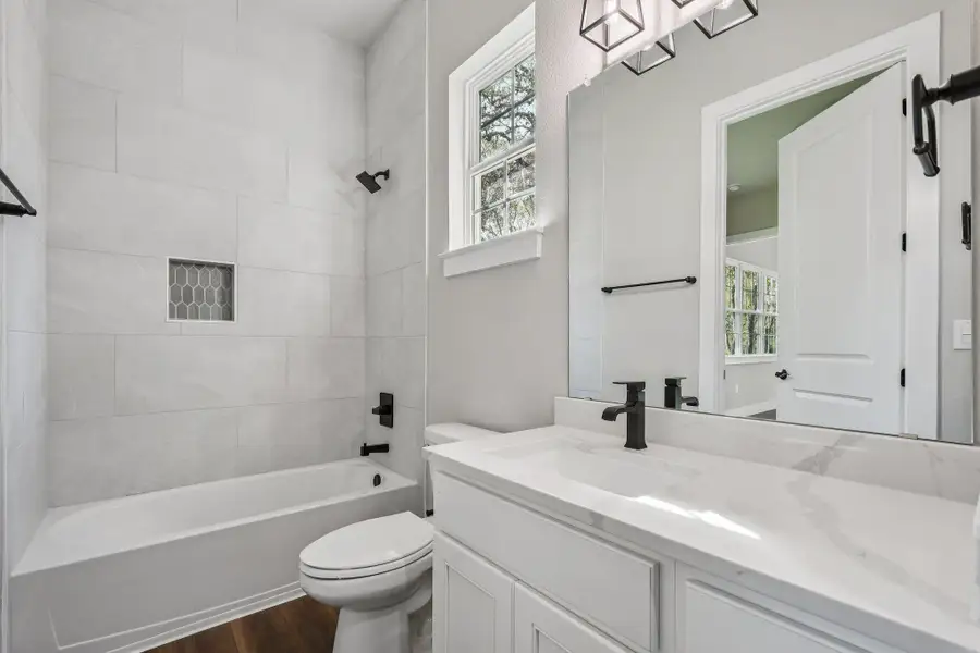 Full bath with plenty of natural light, shower / bathtub combination, vanity, and dark wood-style flooring