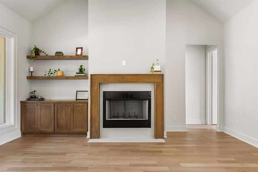 Unfurnished living room with a fireplace with flush hearth, light wood-style floors, and high vaulted ceiling