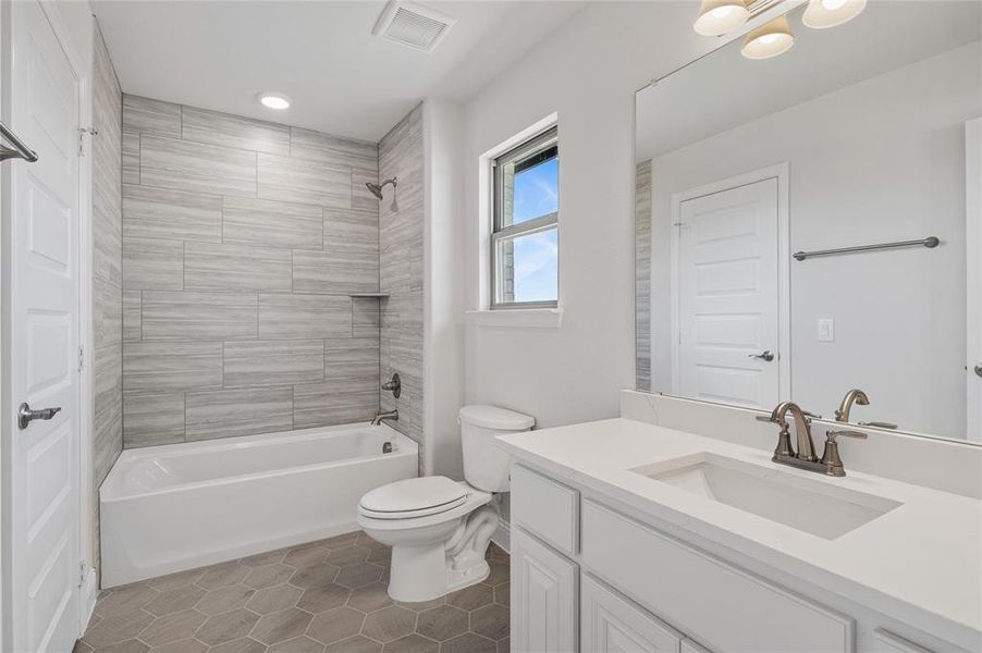 Full bathroom featuring shower / tub combination, dark tile patterned floors, vanity, and recessed lighting