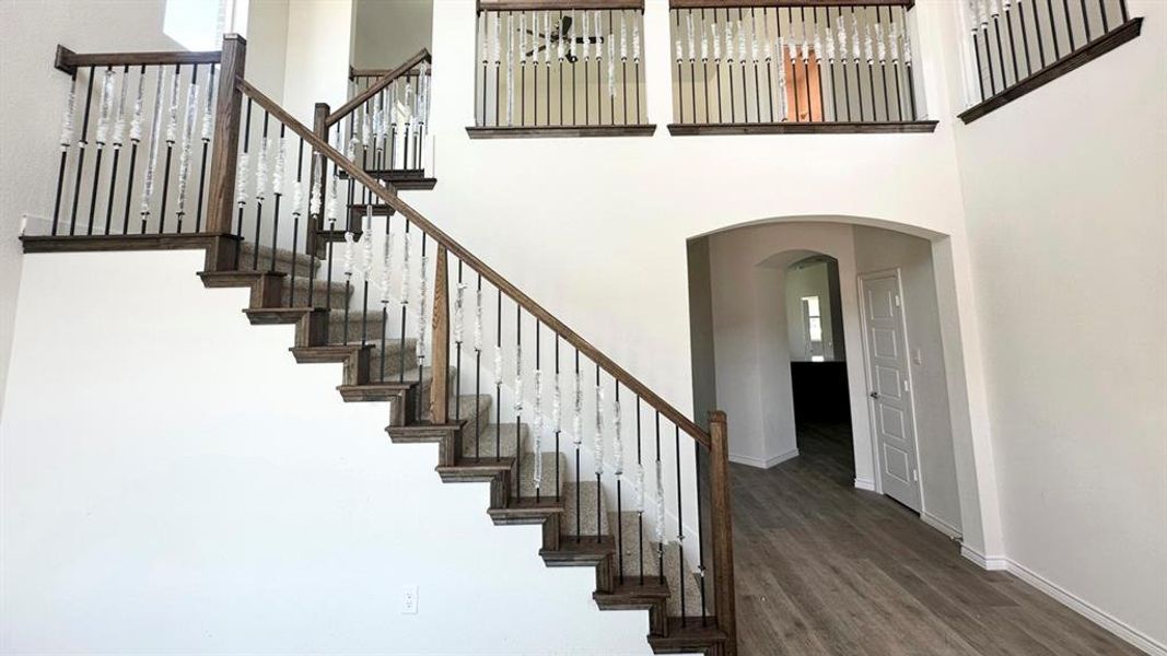 Staircase with arched walkways, a towering ceiling, and wood finished floors Staircase with arched walkways, a towering ceiling, and wood finished floors