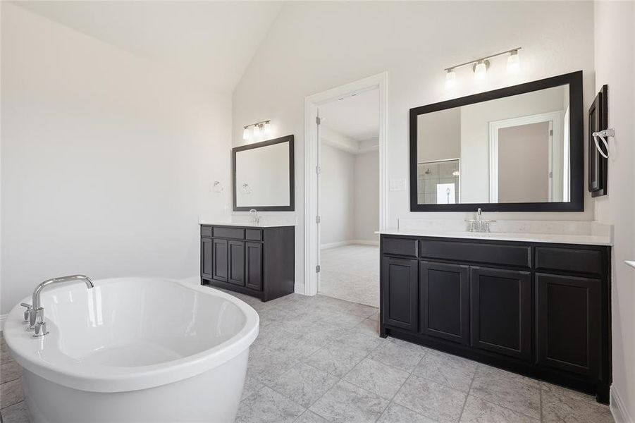 Bathroom featuring two vanities, vaulted ceiling, and a freestanding tub Bathroom featuring two vanities, vaulted ceiling, and a freestanding tub
