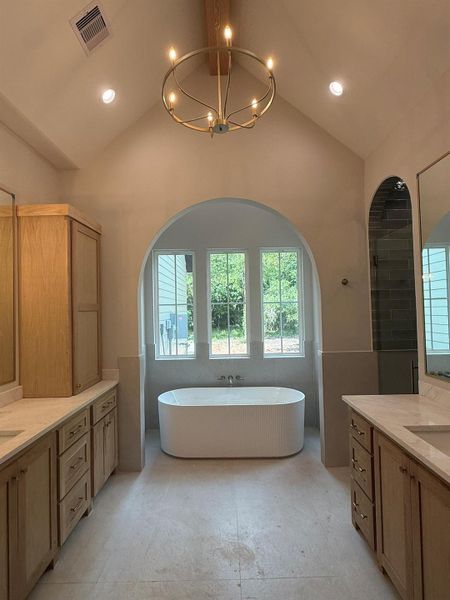 Bathroom with vaulted ceiling, two vanities, a freestanding bath, and a chandelier
