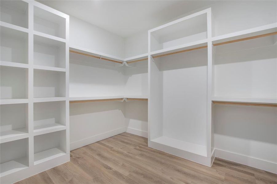 Walk in closet with hardwood / wood-style floors