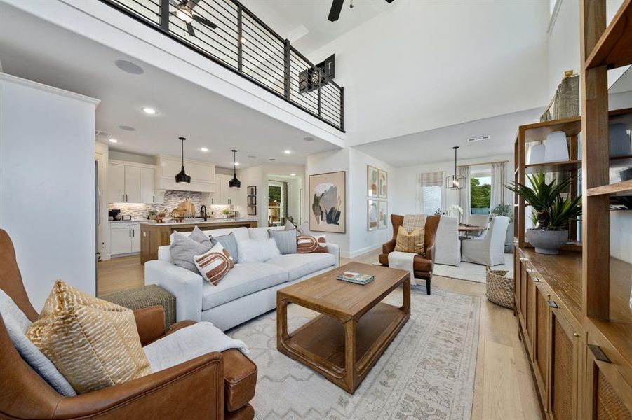 Living room featuring ceiling fan, a towering ceiling, and light hardwood / wood-style flooring