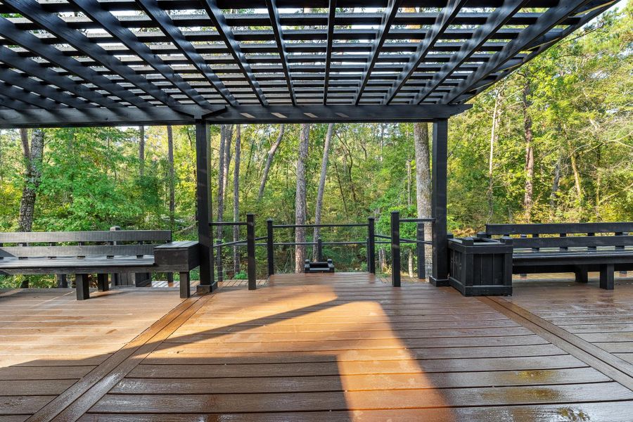 This photo showcases a spacious deck with a sleek black pergola and built-in seating, surrounded by lush greenery, offering a serene outdoor retreat. This photo showcases a spacious deck with a sleek black pergola and built-in seating, surrounded by lush greenery, offering a serene outdoor retreat.
