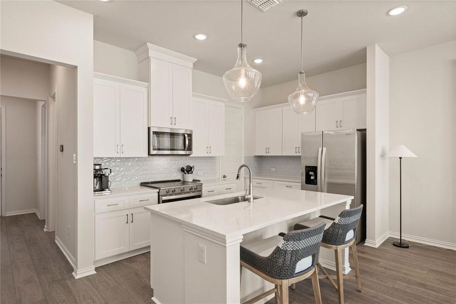 Kitchen featuring sink, white cabinetry, a kitchen breakfast bar, an island with sink, and stainless steel appliances