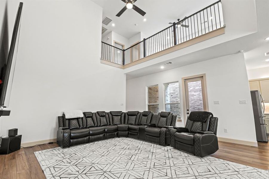 Living room with recessed lighting, light wood-type flooring, a towering ceiling, and ceiling fan