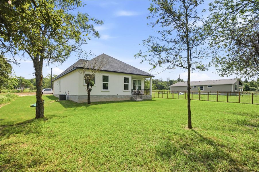 A well-maintained lawn surrounds a charming home with a covered porch and fenced perimeter.