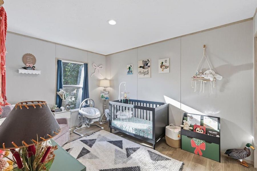 Bedroom with wood finished floors, a crib, and recessed lighting Bedroom with wood finished floors, a crib, and recessed lighting