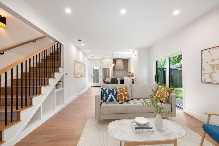 Hardwood floors and recessed lighting elevate this open-concept living space with a stylish staircase. Hardwood floors and recessed lighting elevate this open-concept living space with a stylish staircase.