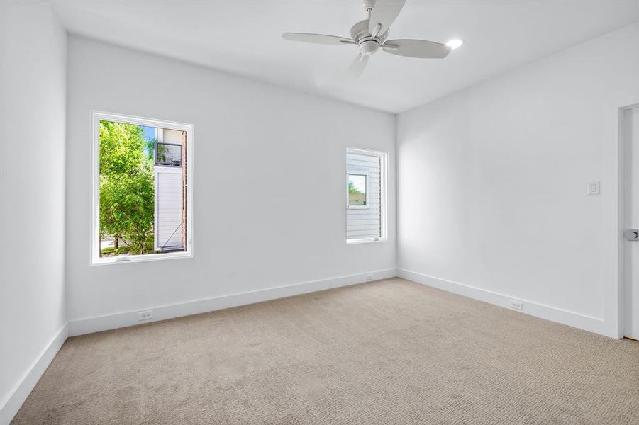 Carpeted empty room featuring a healthy amount of sunlight and ceiling fan