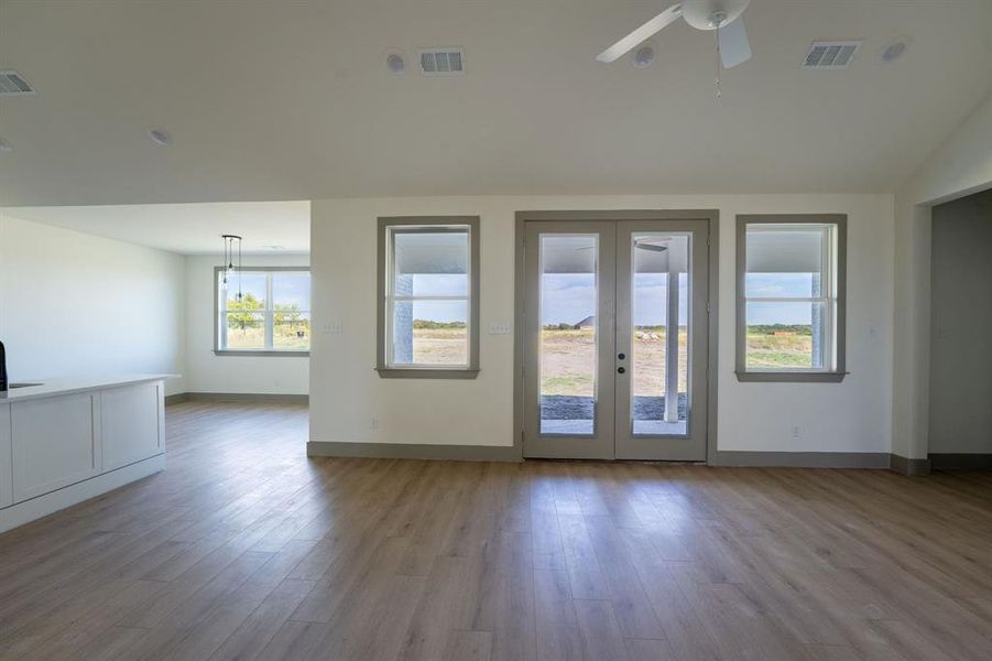 Unfurnished room with french doors, light wood finished floors, and a ceiling fan Unfurnished room with french doors, light wood finished floors, and a ceiling fan