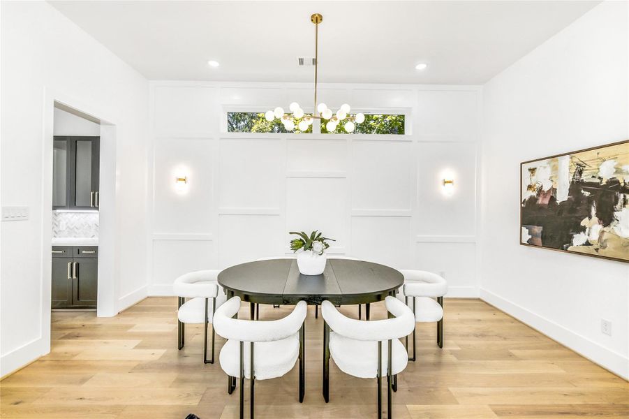 Sophisticated yet inviting, this formal dining area exudes modern elegance with clean architectural wall detailing, a designer chandelier, and natural white-oak flooring. Oversized transom windows flood the space with light, creating an ideal setting for dinner parties, quiet evenings, or executive entertaining. The craftsmanship and proportion reflect the precision of a true luxury build.