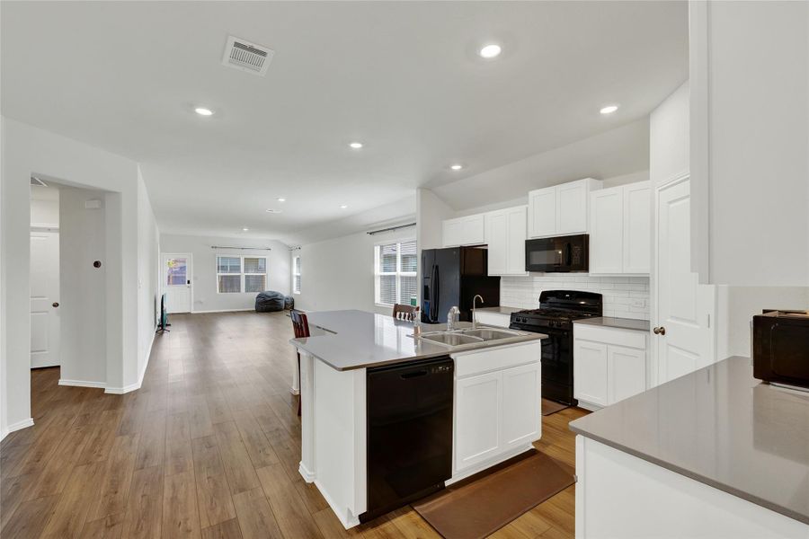 An open-concept living space integrates a well-appointed kitchen with rich hardwood flooring.