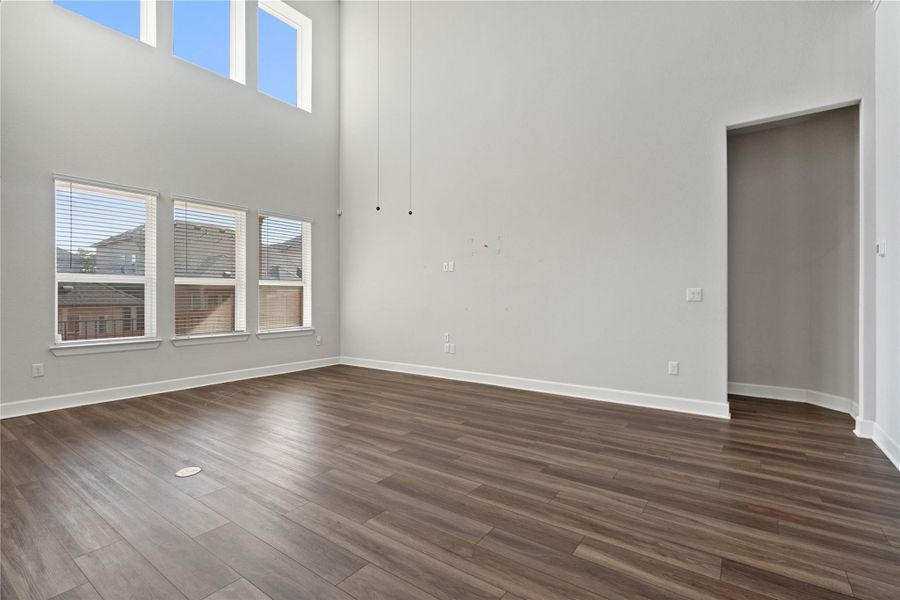 Double-height ceilings and tall windows bring abundant natural light to this wood-floored living area.