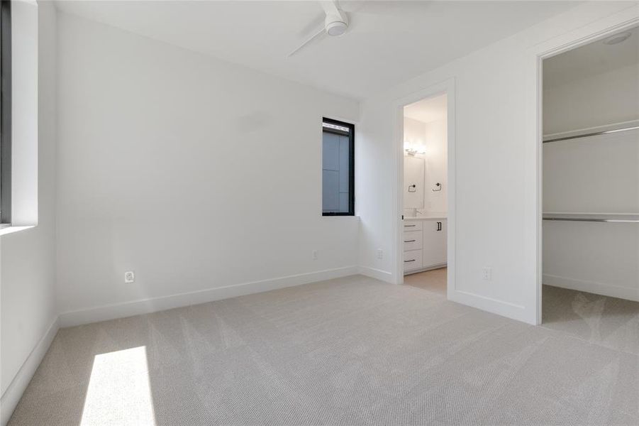 Unfurnished bedroom with ceiling fan, light colored carpet, a closet, and connected bathroom