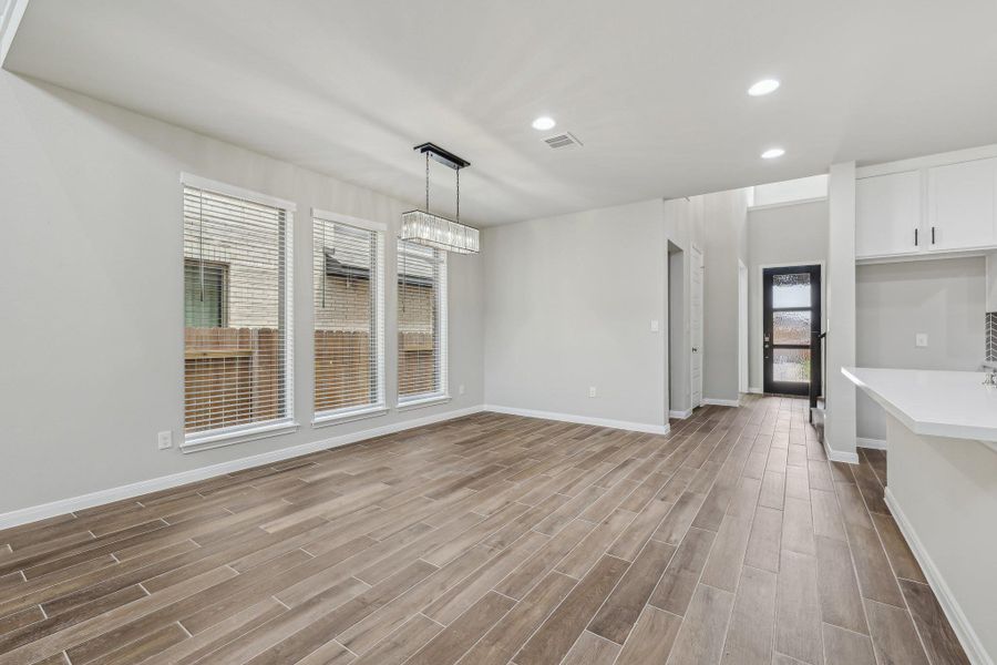 Unfurnished dining area featuring wood finished floors, recessed lighting, and baseboards Unfurnished dining area featuring wood finished floors, recessed lighting, and baseboards