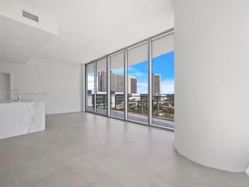 Floor-to-ceiling windows, stone-finish kitchen island, large-format tile flooring, and curved architectural wall Floor-to-ceiling windows, stone-finish kitchen island, large-format tile flooring, and curved architectural wall