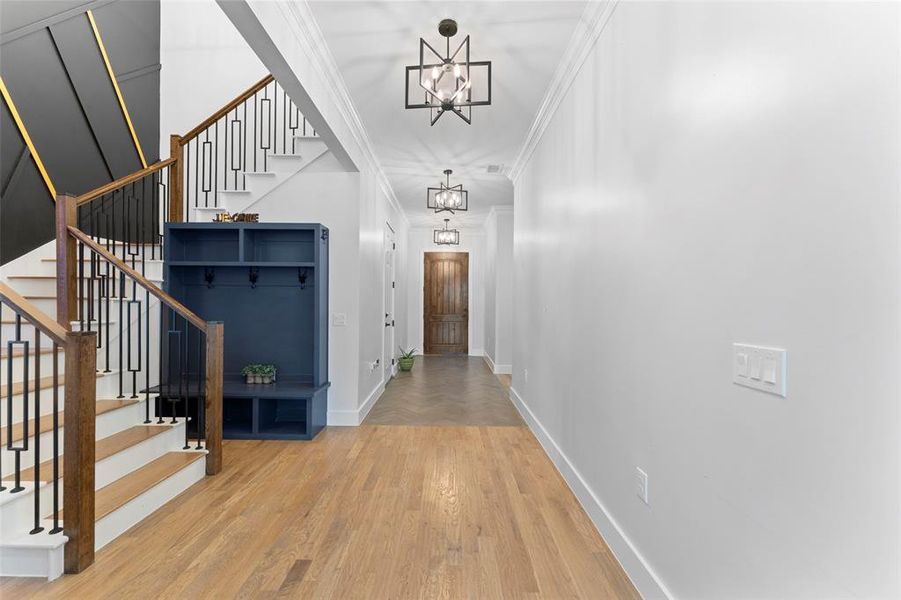 Hall featuring ornamental molding, light wood-type flooring, stairs, and a chandelier Hall featuring ornamental molding, light wood-type flooring, stairs, and a chandelier