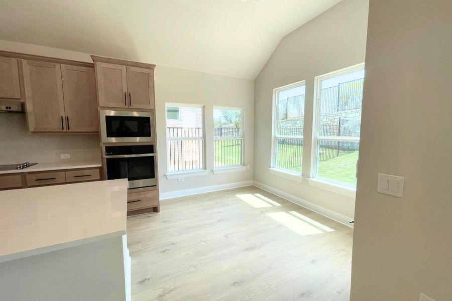 A sunlit breakfast area adjacent to the kitchen boasts high ceilings and tall windows. A sunlit breakfast area adjacent to the kitchen boasts high ceilings and tall windows.