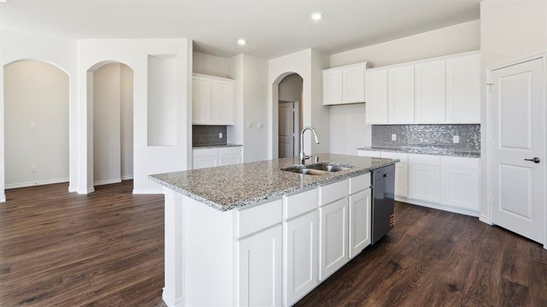 Kitchen with arched walkways, white cabinetry, backsplash, light stone countertops, and dark wood-type flooring Kitchen with arched walkways, white cabinetry, backsplash, light stone countertops, and dark wood-type flooring