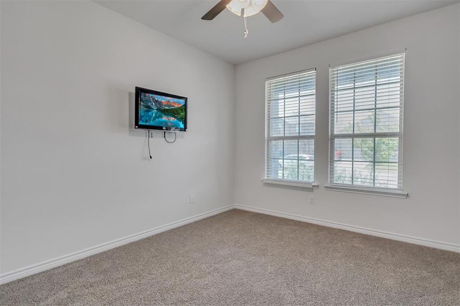 Carpeted spare room featuring ceiling fan and a healthy amount of sunlight