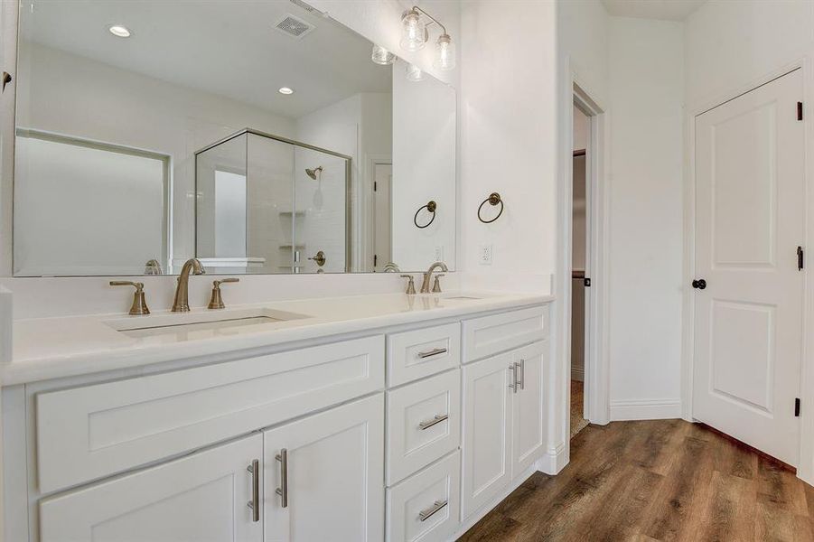 Bathroom featuring dual vanity, hardwood / wood-style flooring, and a shower with door