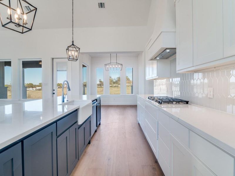 Kitchen with white cabinetry, hanging light fixtures, light wood-style flooring, a chandelier, and light stone countertops