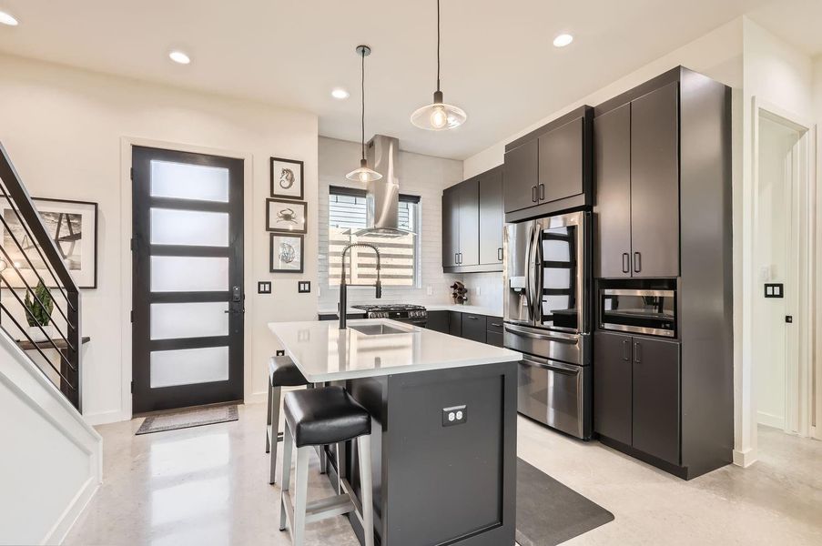 Quartz countertops and stainless-steel appliances, including a gas range with double ovens, elevate the kitchen’s sleek design.