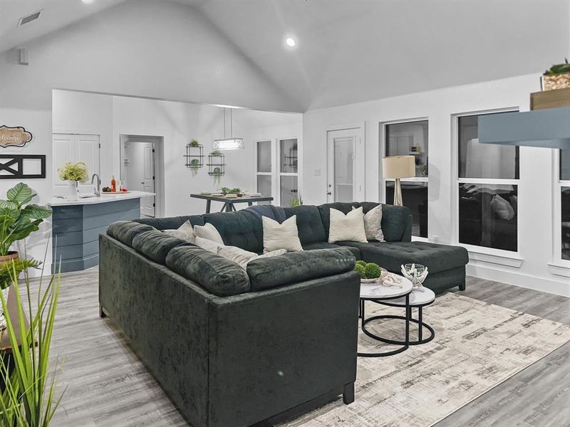 Living room with light hardwood / wood-style flooring and high vaulted ceiling