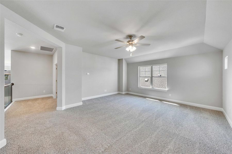 Unfurnished room with light carpet, ceiling fan, and lofted ceiling Unfurnished room with light carpet, ceiling fan, and lofted ceiling