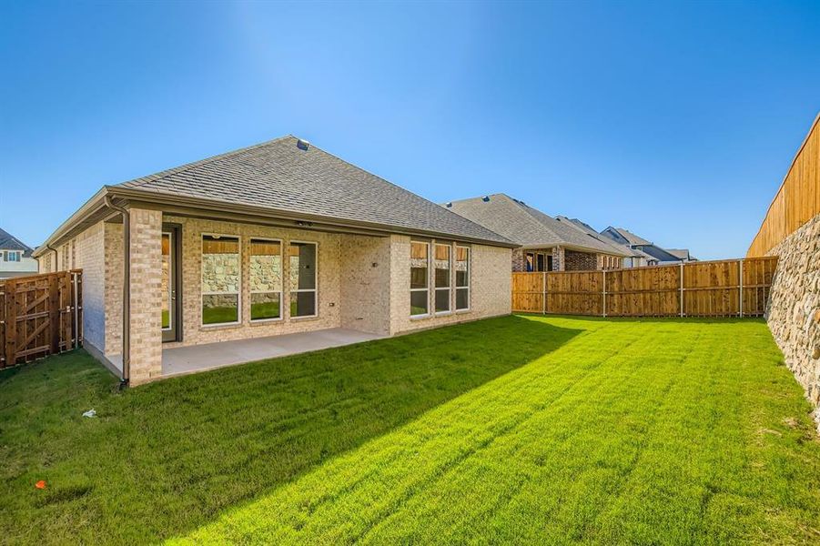 Rear view of house featuring a shingled roof, brick siding, a patio, and a fenced backyard