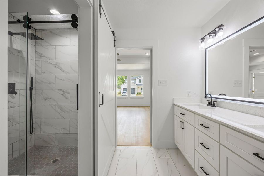 Full bath with marble look tiles, double vanity, a shower stall, and recessed lighting Full bath with marble look tiles, double vanity, a shower stall, and recessed lighting