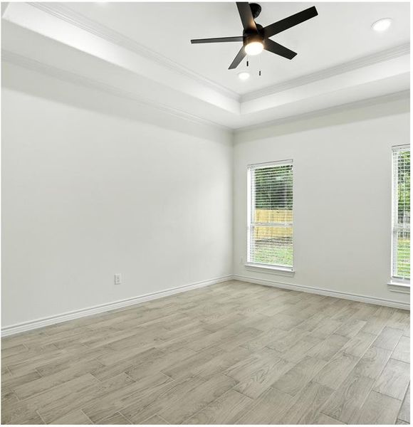 Unfurnished room with light wood-style flooring, crown molding, a raised ceiling, recessed lighting, and ceiling fan