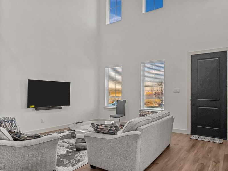 Living room with a high ceiling and light hardwood / wood-style flooring