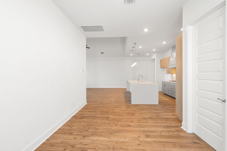 A pristine open-concept space features warm wood flooring and a luminous kitchen with modern pendant lighting.