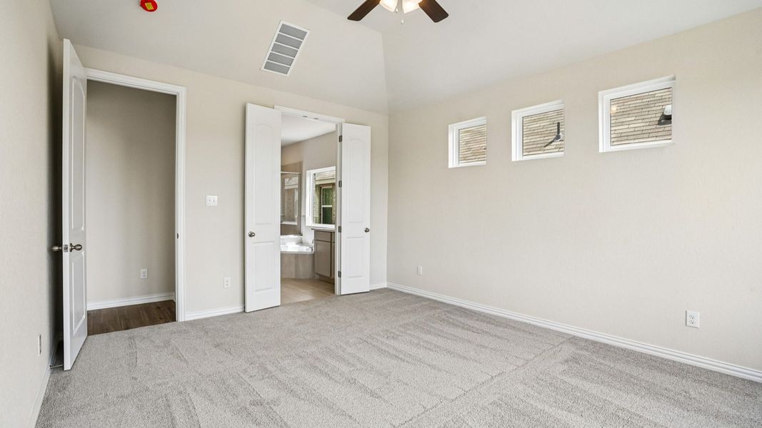 Owner's Suite features plenty of windows allowing natural light to flow, a raised ceiling, and ceiling fan