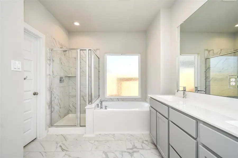 Experience a spa-like escape right in the heart of your primary bathroom. Theexpansive walk-in shower, surrounded by tile, and the distinctive garden tubwith unique accents elevate your daily routine. The sophisticated vanity,featuring double sinks, light-colored countertops, contemporary hardware, andbright recessed lighting, adds both style and functionality to the space. Sample photo of completed home with similar floor plan. Actual colors and selections may vary.