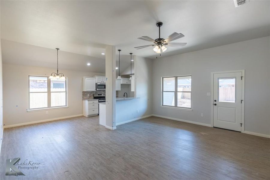 Unfurnished living room featuring plenty of natural light, wood finished floors, ceiling fan, and recessed lighting