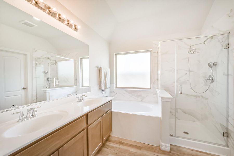 Welcome to your spa like ensuite! This space features a large vanity with upgraded dual sinks, chrome finishes, and stained maple cabinets. A soaking tub and separate walk in shower are divided by a half wall with clear glass, and an obscure window over the tub adds privacy without sacrificing natural light. Welcome to your spa like ensuite! This space features a large vanity with upgraded dual sinks, chrome finishes, and stained maple cabinets. A soaking tub and separate walk in shower are divided by a half wall with clear glass, and an obscure window over the tub adds privacy without sacrificing natural light.
