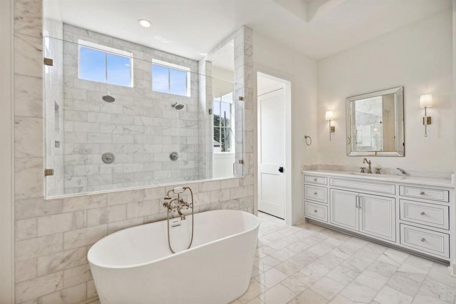 STUNNING primary bath with marble countertops, marble tile floors and shower surround.