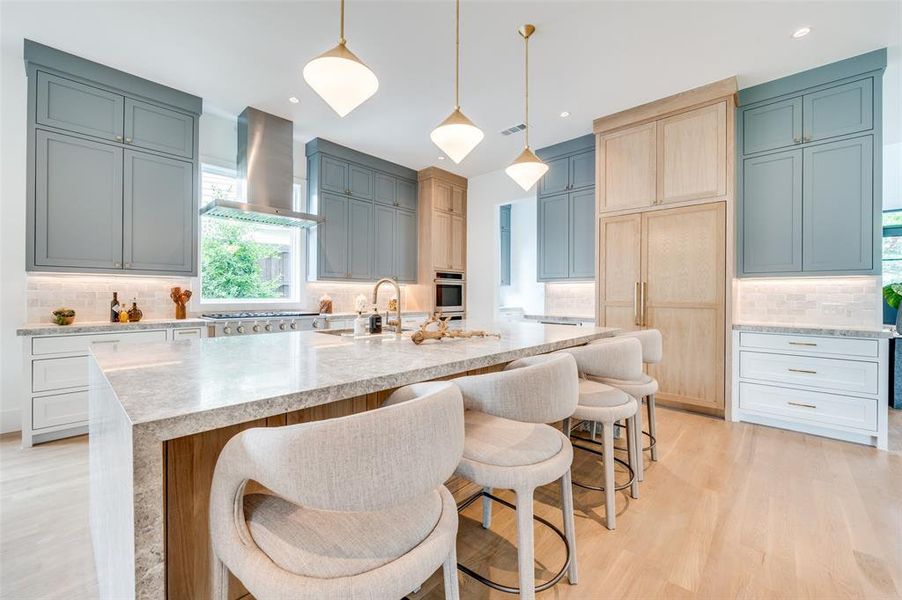 Kitchen featuring tasteful backsplash, appliances with stainless steel finishes, wall chimney exhaust hood, and a center island with sink