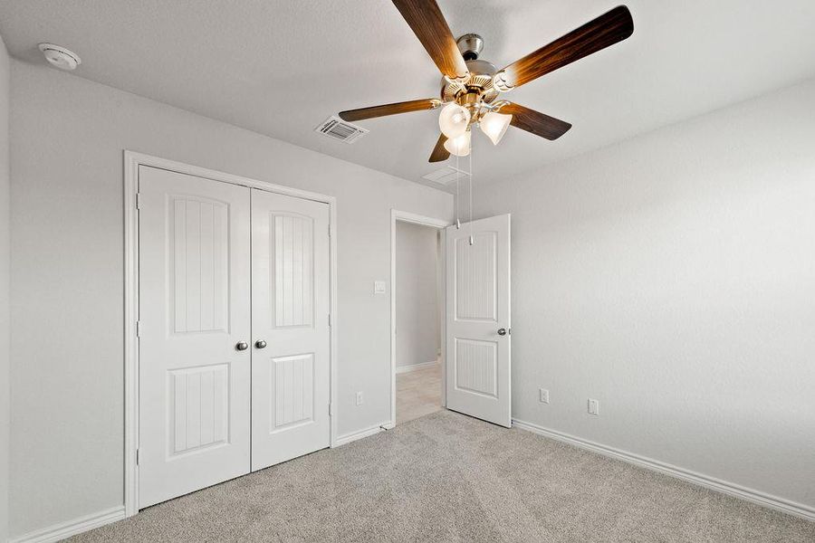 Unfurnished bedroom featuring carpet, a closet, and a ceiling fan